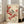 May include: Large framed botanical art print leaning against white wall in bright living room corner next to beige upholstered chair. Artwork shows small bird with black cap and wings perched on branch with clusters of bright red berries against cream background in traditional Japanese style. Light wooden frame, positioned on hardwood floor near tall windows.
