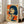 May include: A framed vintage-style Japanese poster featuring a woman with dark bob haircut and bangs smoking a cigarette, rendered in retro comic book style with bold orange and blue colors on cream background. The artwork includes Japanese text characters and is displayed in a white frame leaning against a wall next to a beige sofa in a bright, minimalist living room with white walls and large windows.