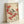 May include: Framed vintage Japanese-style botanical print showing a small black, white and gray bird perched on brown branches with clusters of bright red berries. The artwork has a cream background with delicate brushwork in traditional Asian art style. Light wood frame leans against white wall, casting soft shadow.