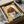 May include: Framed artwork featuring an anime-style girl with brown bob haircut and large eyes on yellow background, displayed in black frame inside cardboard shipping box with protective wrapping materials and wooden support pieces visible around the package.