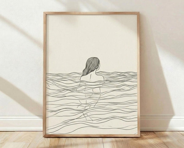 May include: Framed minimalist line art poster showing a woman with long hair submerged in flowing wavy water lines, displayed in light wood frame against cream textured wall with soft natural lighting and shadows on wooden floor