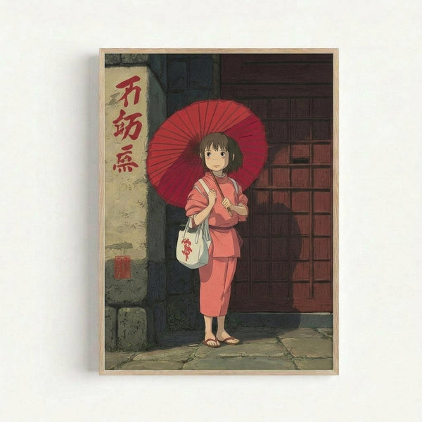 A framed anime-style poster showing a young girl with short brown hair wearing a pink kimono and holding a red traditional Japanese umbrella. She stands on stone pavement in front of a traditional wooden building with a white banner displaying red Japanese characters. The girl carries a white bag and wears brown sandals. The artwork features Studio Ghibli's distinctive animation style with warm, muted colors and detailed architectural elements. The poster is displayed in a light wooden frame aga