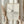 May include: Hands holding a light wood framed minimalist line drawing showing a woman's silhouette submerged in flowing water waves, displayed against soft white curtains with dried pampas grass visible to the side, natural lighting creating gentle shadows across the cream-colored artwork
