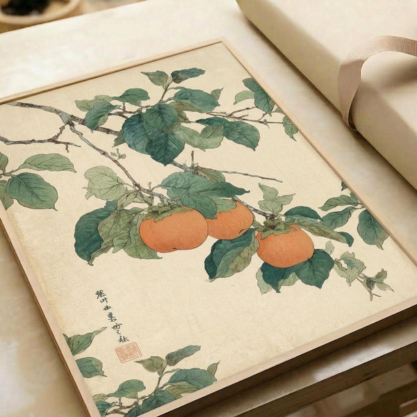May include: Japanese botanical illustration featuring persimmon branches with orange-red fruit and green leaves on cream paper, displayed in an open book or portfolio with white ribbon binding, photographed on a neutral surface in soft natural lighting