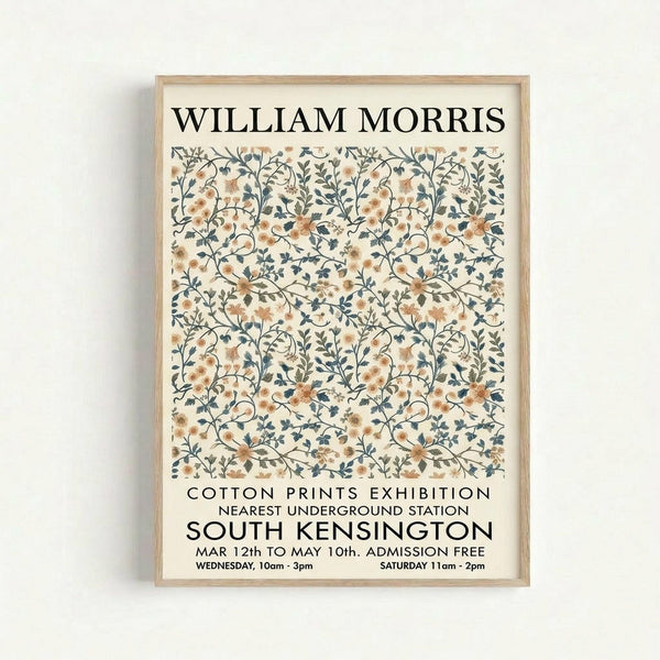 May include: Framed vintage-style exhibition poster with William Morris floral pattern in peach and blue-gray tones, featuring intertwining botanical motifs on cream background. Light wood frame hangs on white wall. Text shows Cotton Prints Exhibition details for South Kensington location with dates and admission information in black typography.