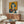 May include: Framed vintage-style Japanese Coca-Cola poster with woman in blue bob haircut holding Coke bottle against orange background, displayed above mid-century walnut credenza in modern living room with white curved chair, round glass coffee table, and brass floor lamp