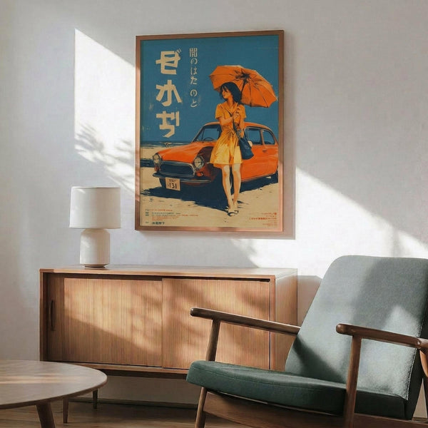 May include: Framed vintage-style Japanese poster featuring woman in orange dress with matching umbrella standing beside classic orange car on beach. Blue sky background with Japanese text. Wooden sideboard below holds white ceramic table lamp. Mid-century modern sage green upholstered armchair with wooden arms positioned nearby. Warm sunlight streams across white wall creating geometric shadows.
