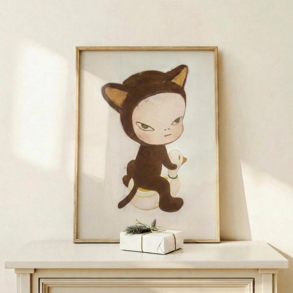 May include: Framed poster print displayed on light wood shelf against white wall, featuring whimsical illustration of pale child-like figure in brown cat costume with pointed ears riding small white duck. Small white wrapped gift with evergreen sprig sits on shelf beside thin natural wood frame. Soft natural lighting creates gentle shadows on minimal, clean styling.