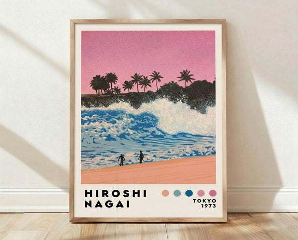 May include: Framed vintage-style beach poster showing pink sunset sky, dark silhouetted palm trees, blue ocean waves with white foam, coral-pink sand, and two small walking figures. Features color palette dots and Tokyo 1973 text below artwork. Light wooden frame displayed on wooden floor against white textured wall with soft shadows.