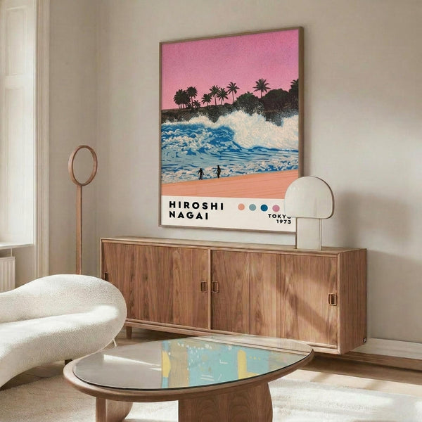 May include: Framed poster showing tropical beach scene with pink sky, palm trees, blue waves, coral sand, and two silhouetted figures. Displayed above wooden mid-century credenza with white table lamp. Room features cream walls, white upholstered swivel chair, oval glass coffee table, and natural lighting creating warm shadows across polished floor.