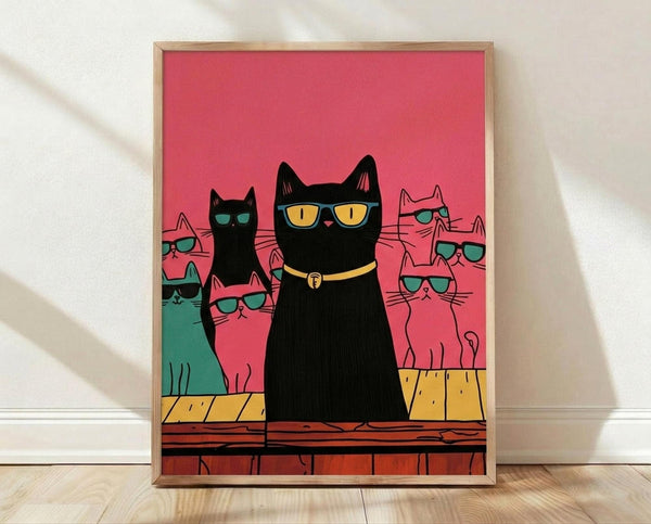 May include: Framed poster print leaning against white wall on light wood floor with dramatic shadow. Features stylized illustration of black cat with yellow sunglasses and collar as main subject, surrounded by smaller cats in pink, teal, and black all wearing blue-green sunglasses. Vibrant coral pink background with yellow and orange brick ledge. Simple light wood frame, approximately 16x20 inches scale.