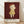 May include: Framed poster print leaning against white wall on light wood floor. Features minimalist illustration of pale child with reddish bob haircut wearing yellow dress against deep burgundy background. Artist name "YOSHITOMO NARA" and Japanese text with exhibition dates "1992年8月31日～10月31日" printed below artwork. Natural wood frame, soft window lighting creating gentle shadows on white fabric backdrop.