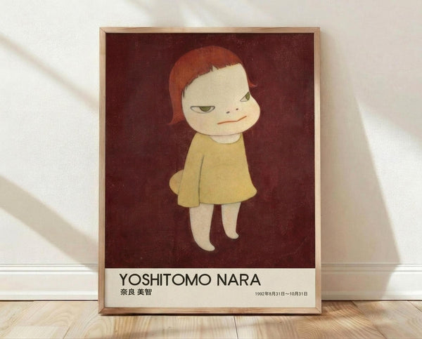 May include: Framed poster print leaning against white wall on light wood floor. Features minimalist illustration of pale child with reddish bob haircut wearing yellow dress against deep burgundy background. Artist name "YOSHITOMO NARA" and Japanese text with exhibition dates "1992年8月31日～10月31日" printed below artwork. Natural wood frame, soft window lighting creating gentle shadows on white fabric backdrop.