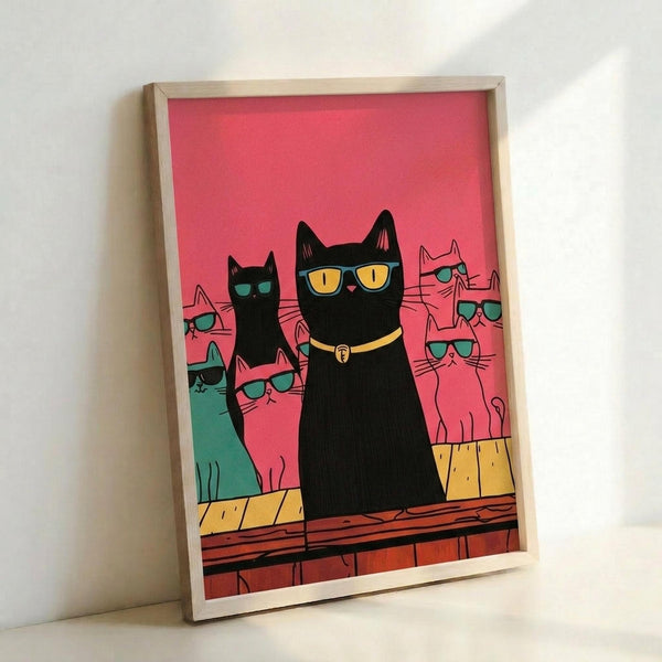 May include: Framed poster print featuring stylized cats wearing sunglasses against a coral pink background. The main black cat in center wears yellow sunglasses and a collar, surrounded by pink, green, and black cats all sporting teal sunglasses. The cats sit on wooden planks with a yellow textured surface behind. The artwork is displayed in a light wood frame leaning against a white wall.