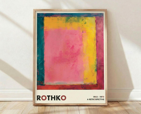 May include: Framed abstract art poster with vibrant pink, yellow, orange, and teal color blocks in Rothko's signature style, displayed against white textured wall on light wood floor. Natural lighting creates soft shadows across the scene. The artwork features bold rectangular forms with painterly edges and rich color transitions.