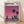 May include: Framed poster print leaning against white wall on light wood floor. Artwork shows purple-pink gradient sky with silhouetted city skyline, two prominent palm trees, and buildings reflected in water below. Light wood frame surrounds the vintage-style illustration with "HIROSHI NAGAI" text at top and Japanese characters beneath.