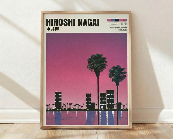 May include: Framed poster print leaning against white wall on light wood floor. Artwork shows purple-pink gradient sky with silhouetted city skyline, two prominent palm trees, and buildings reflected in water below. Light wood frame surrounds the vintage-style illustration with "HIROSHI NAGAI" text at top and Japanese characters beneath.