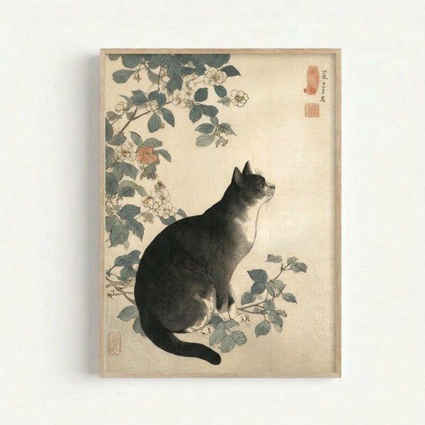 Japanese woodblock print featuring a black and white cat sitting among flowering rose branches. The cat gazes upward with detailed fur rendering in traditional sumi-e style. Delicate pink and white roses with green leaves frame the composition on cream-colored paper. Red artist seals appear in the upper right corner. The artwork is displayed in a simple wooden frame against a white wall.