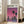 May include: Framed poster with purple-pink sunset sky featuring two tall palm trees and city skyline silhouette reflected in water below. Light wood frame leaning against white wall next to beige upholstered chair in bright living room with large windows and hardwood floors.