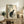 May include: Japanese woodblock print artwork featuring a gray and white cat sitting beneath flowering rose branches with green leaves, displayed in a light wood frame on a rustic wooden sideboard alongside fern plant, ceramic vase, and books in a neutral-toned living room setting