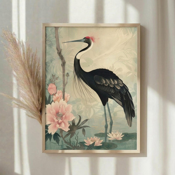 May include: Framed vintage-style botanical art print featuring an elegant black crane with red crown crest and long curved neck, surrounded by soft pink peonies and lotus flowers in muted green and cream tones, displayed on white wall next to dried pampas grass stems with natural window lighting creating gentle shadows