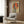 May include: Vintage-style poster featuring woman in blue cheongsam dress sitting on stool against large red circle, with Chinese characters, displayed in modern living room with beige armchair, geometric pillow, brass floor lamp, and wood paneled wall