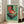 May include: Framed vintage-style poster with turquoise green background featuring illustrated record player with open lid and red vinyl record. Japanese text appears on right side with "JAPANESE SOUNDS" in English. Cream-colored wooden frame leans against white wall next to beige upholstered chair in bright room with large windows.