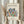 May include: Hands holding a framed museum poster print featuring Matisse's colorful cut-out botanical design with blue, green, orange and red leaf shapes arranged in a circular bouquet pattern. Light wooden frame against cream background with dried pampas grass visible to the left side.