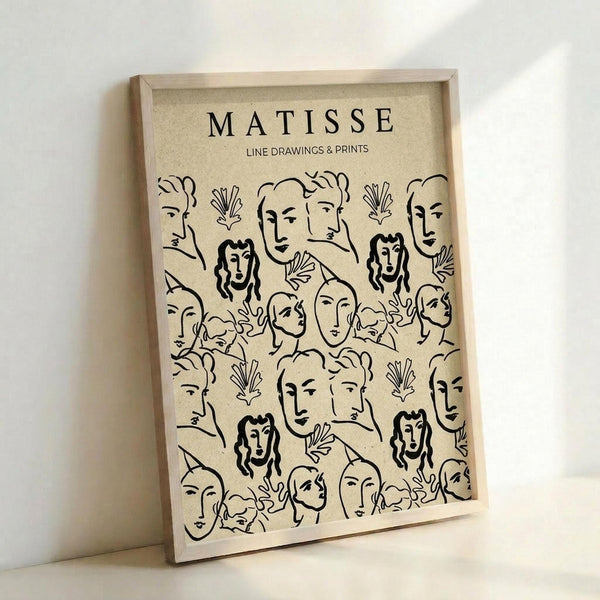 May include: Framed poster with beige background featuring black line drawing pattern of various human faces and botanical elements in Matisse's minimalist style. Light wood frame displayed against white wall, showing the repeating design of profile and front-facing portraits interspersed with simple leaf motifs.