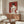 May include: Red and white art print showing woman in draped clothing holding roses, displayed above wooden credenza in modern living room with white curved chair, glass coffee table, and floor lamp