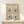 May include: Framed beige poster with black line drawings in Matisse's distinctive style, featuring repeated faces and botanical elements in a pattern. Light wood frame on white wooden shelf against cream wall, with small wrapped gift box beside it.