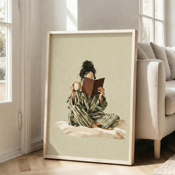 A framed illustration of a woman in a striped robe sitting on a bed and reading a book.