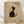 May include: Framed poster print featuring a minimalist black and white cat illustration in Japanese ink painting style, sitting and looking upward with whiskers and simple line details, displayed on light wood flooring against white wall with natural lighting and shadows, in thin light wood frame on beige textured background with red seal stamp in corner.