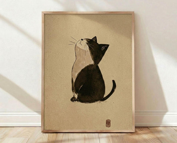 May include: Framed poster print featuring a minimalist black and white cat illustration in Japanese ink painting style, sitting and looking upward with whiskers and simple line details, displayed on light wood flooring against white wall with natural lighting and shadows, in thin light wood frame on beige textured background with red seal stamp in corner.
