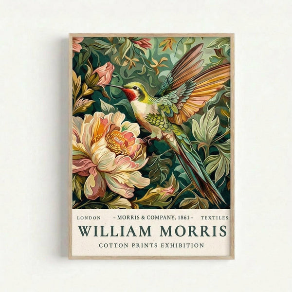 Framed vintage-style botanical poster featuring a vibrant hummingbird with outstretched wings hovering near a large pink peony flower. The bird displays green, red, yellow and white plumage against a rich teal background filled with decorative leaves and smaller pink buds. The illustration has an ornate Victorian textile pattern aesthetic. Below the artwork is cream-colored text reading "London - Morris & Company, 1861 - Textiles" and "William Morris Cotton Prints Exhibition" in dark let