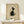 May include: Framed minimalist cat artwork in light wood frame displayed on pale wooden surface against cream wall. Black and white tuxedo cat sits looking upward in Japanese ink wash style on beige textured background. Small wrapped white gift box with evergreen sprig sits beside frame. Soft natural lighting creates gentle shadows.
