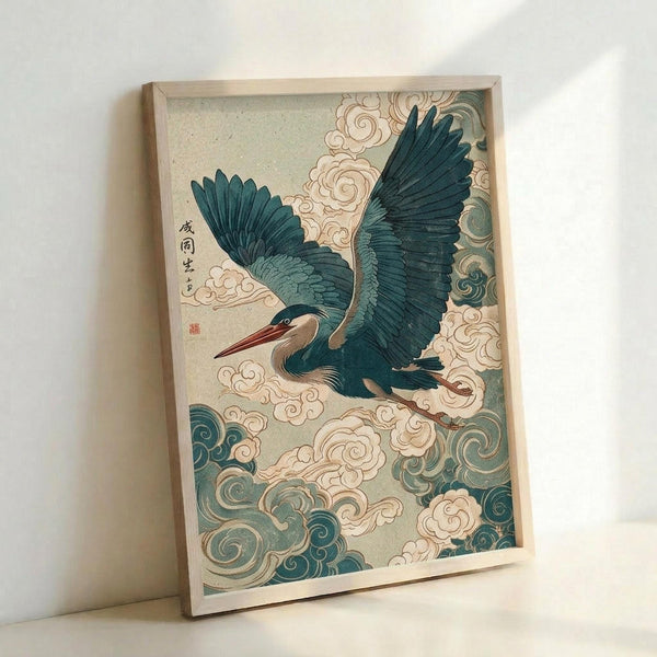 Framed Japanese-style woodblock print featuring a blue-green heron in flight with outstretched wings against swirling clouds and wind patterns. The artwork displays traditional ukiyo-e aesthetics with teal, cream, and pale green colors on textured paper. Japanese calligraphy and a red seal appear in the upper left corner. The print is mounted in a light wooden frame and photographed leaning against a white wall.