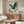 May include: Japanese-style artwork featuring a blue-green heron with outstretched wings flying through stylized clouds, displayed in a thin frame above a wooden sideboard. The print shows traditional Asian artistic elements with teal and cream colors. Modern living room setting with white curved chair, glass coffee table, and minimalist decor.