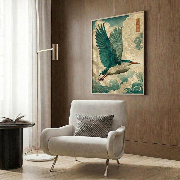 May include: Japanese-style artwork featuring a blue-green heron with outstretched wings flying through stylized cream and teal clouds, displayed as a framed print on wood-paneled wall above a beige upholstered armchair with geometric patterned pillow, alongside a brass floor lamp and dark round side table with open book in a modern neutral-toned room setting.