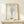 May include: Framed botanical line drawing print in light wood frame showing dried flowers in glass vase, displayed on pale wood shelf against cream wall. Blue ink illustration on textured cream paper with "DRIED FLOWERS" and "1970s SPECIMEN" text. Small wrapped gift box with greenery sits beside frame. Minimalist Scandinavian-style home decor setting with soft natural lighting.