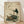 May include: Framed Japanese-style artwork showing a white stork with black wing feathers and orange beak standing on rocks beside a brown turtle, surrounded by green foliage. The vintage-style print features muted earth tones on aged paper background with traditional Chinese characters and red seals. Wood frame sits on light wooden flooring against white wall with soft natural lighting creating subtle shadows.