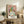 May include: Framed Picasso-style cubist portrait print displayed on rustic wooden sideboard in cozy living room setting. Artwork features abstract female figure with green and yellow face, pink background, rendered in characteristic geometric style. Natural wood frame complements warm interior with fern plant, ceramic vase, books, and beige upholstered furniture visible.