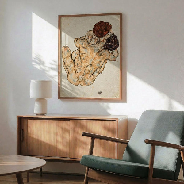 May include: Framed art print featuring two embracing figures in warm earth tones and muted colors, displayed above a mid-century modern wooden credenza with sliding doors. A white ceramic table lamp sits on the credenza, and a sage green upholstered armchair with wooden frame is positioned nearby. Natural sunlight casts geometric shadows across the white wall, creating a serene living room setting with vintage modern furniture.
