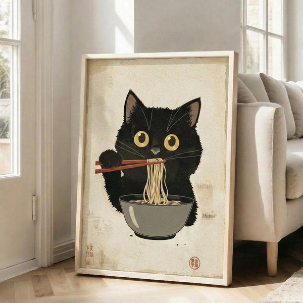 May include: Framed poster print featuring a black cat with large yellow eyes eating ramen noodles with chopsticks from a gray bowl, rendered in Japanese ukiyo-e woodblock print style with beige aged background and red stamp seal. Light wood frame leans against white wall next to beige upholstered chair in bright room with tall windows.
