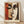 May include: Framed cubist-style art print featuring abstract faces in geometric shapes, displayed against white wall. Artwork shows warm earth tones - oranges, browns, and creams - with stylized eyes and facial features in Picasso-inspired design. Light wood frame sits on wooden floor with natural lighting casting soft shadows.