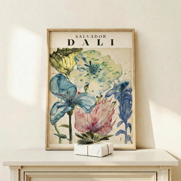 May include: Framed botanical art print featuring watercolor flowers in blue, green, yellow and pink tones with "Salvador Dali" text at top, displayed on light wood shelf against white wall with small white decorative object nearby. Vintage-style floral illustration with delicate petals and stems in soft, dreamy colors within natural wood frame.