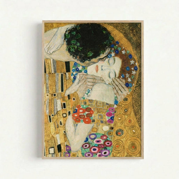 Framed reproduction of Klimt's famous painting showing two embracing figures against an ornate golden background. The man has dark hair and wears geometric patterned robes in gold and black rectangles. The woman has flowing hair adorned with flowers and colorful circular patterns covering her dress. Both figures are rendered in Klimt's distinctive Art Nouveau style with elaborate decorative elements, swirling motifs, and rich jewel tones of blue, red, and purple against shimmering gold leaf text