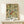 May include: Framed botanical poster with intricate floral pattern featuring green leaves, golden flowers, red berries, and ornate scrollwork in William Morris Victorian decorative style, displayed on light wood shelf next to small white wrapped gift with evergreen sprig against cream colored wall