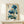 May include: Framed botanical artwork featuring blue poppies with oriental calligraphy text, displayed on a light wood shelf against a cream wall. The vintage-style print shows detailed watercolor flowers in various shades of blue with green stems and seed pods. A small white wrapped gift sits in front of the thin wooden frame.