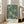 May include: Framed poster with intricate teal and cream floral pattern featuring large chrysanthemums, flowing leaves, and decorative botanical motifs in William Morris Victorian style, displayed on light wooden floor against white wall near beige upholstered chair and tall windows with natural lighting